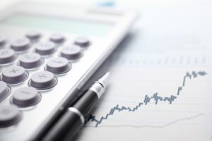 Calculator and ballpoint pen on stock market data chart.