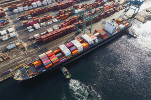 Aerial view of tugboats helping to dock a container ship.