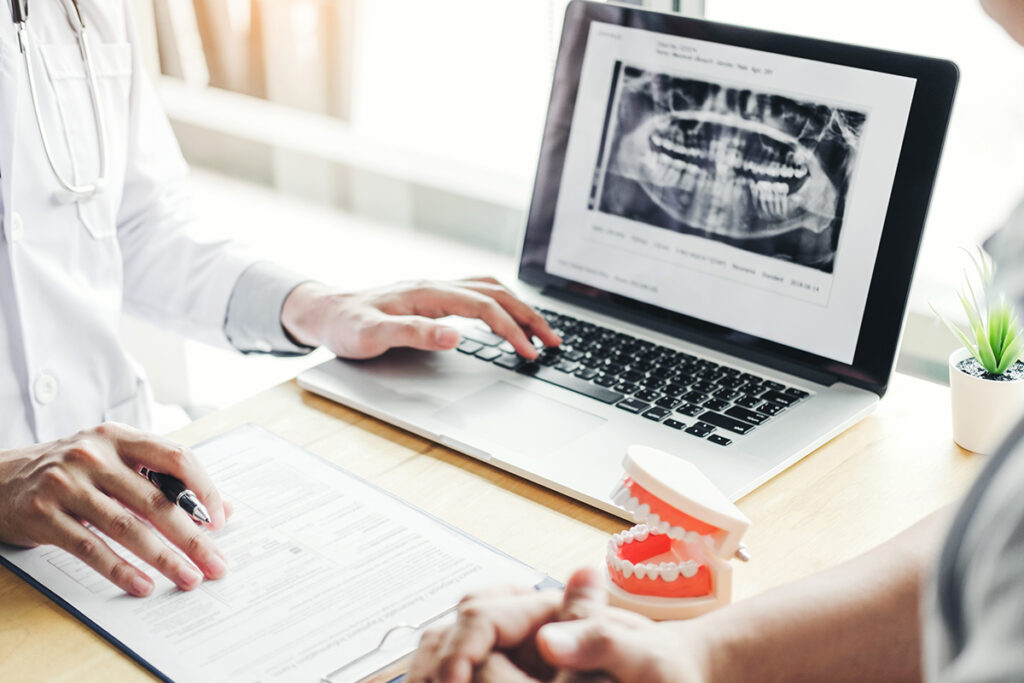 Dentist talking to male patient and presenting results on Dental x-ray film About the problem of the patient in dental office - stock photo