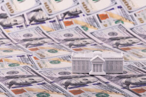 A miniature residence of the President of the United States, the White House, against the backdrop of 100 US dollar bills. - stock photo