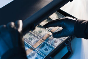 Money in a briefcase with gloved hands - stock photo