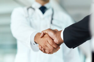 Cropped shot of a doctor shaking hands with a businessman in a hospital