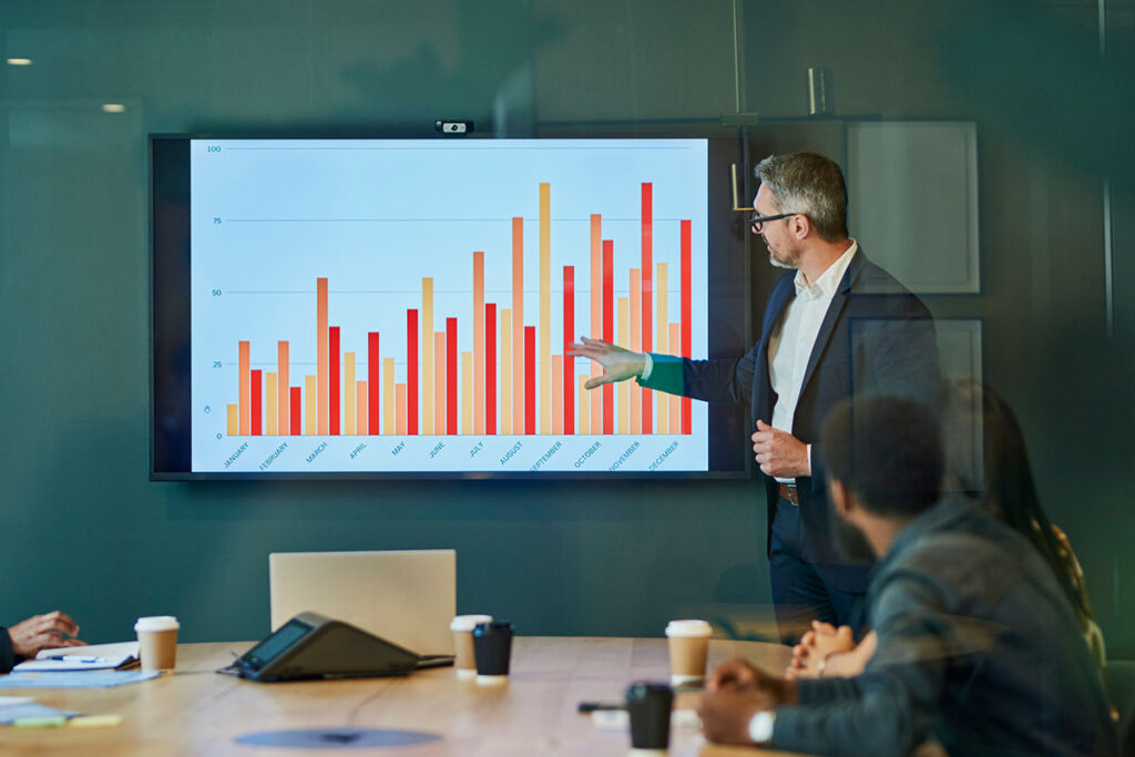 Businessman giving presentation to colleagues in boardroom - stock photo