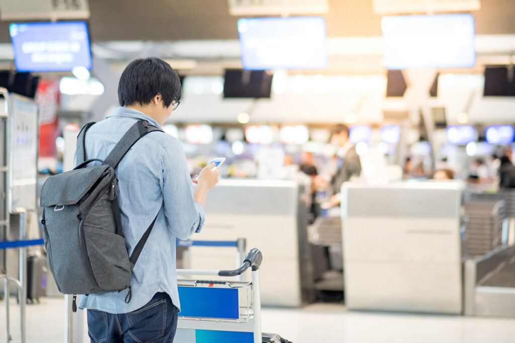 Young asian waiting for drop luggage at airline check-in counter in airport terminal - stock photo