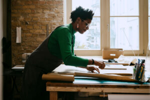 Female artist concentrating while doing craft at table in living room - stock photo