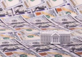 A miniature residence of the President of the United States, the White House, against the backdrop of 100 US dollar bills. - stock photo