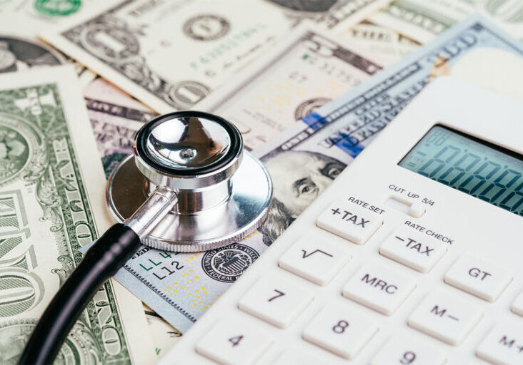 Financial health check, tax or medical and health care expense concept, stethoscope put on FED federal reserve emblem on US dollar banknotes with white calculator, debt and revenue ratio - stock photo